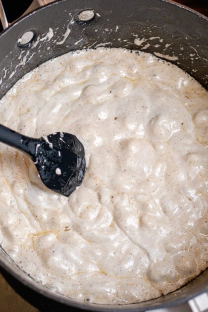 Melted marshmallows in a large pot with black spatula.