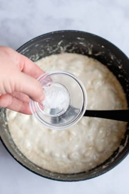 Pouring sea salt in a pot of melted brown butter marshmallows.