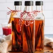 Three bottles of homemade vanilla extract with vanilla beans inside