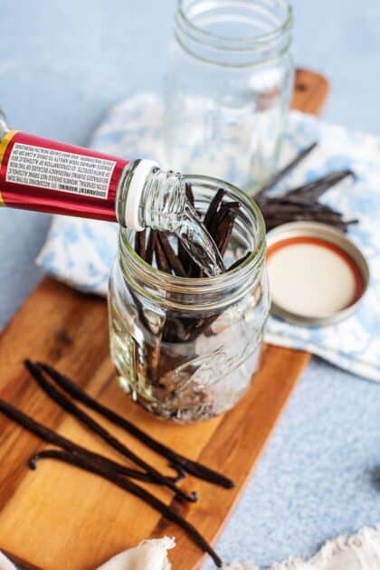 Pouring vodka over vanilla beans in a mason jar