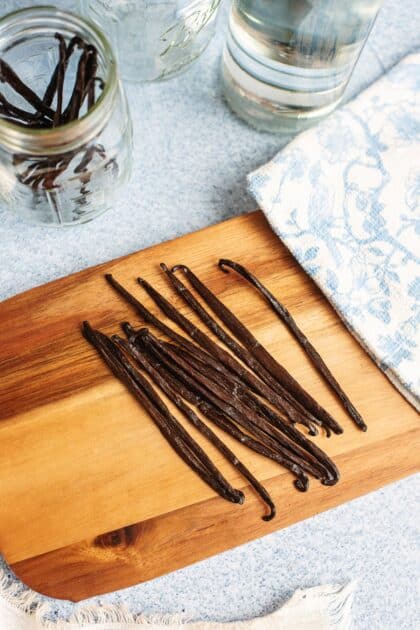 Whole vanilla beans on a wooden cutting board